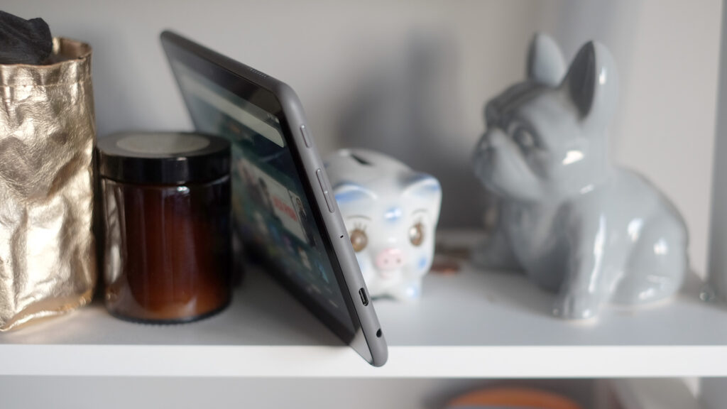 Планшет Amazon Fire HD 8 Plus на полке с декоративными предметами.