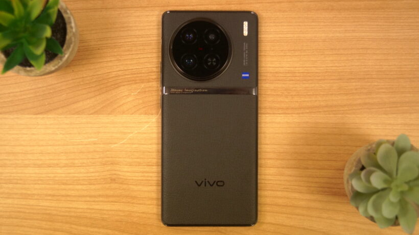 Смартфон Vivo X90 Pro на деревянной поверхности с крупным планом камеры.