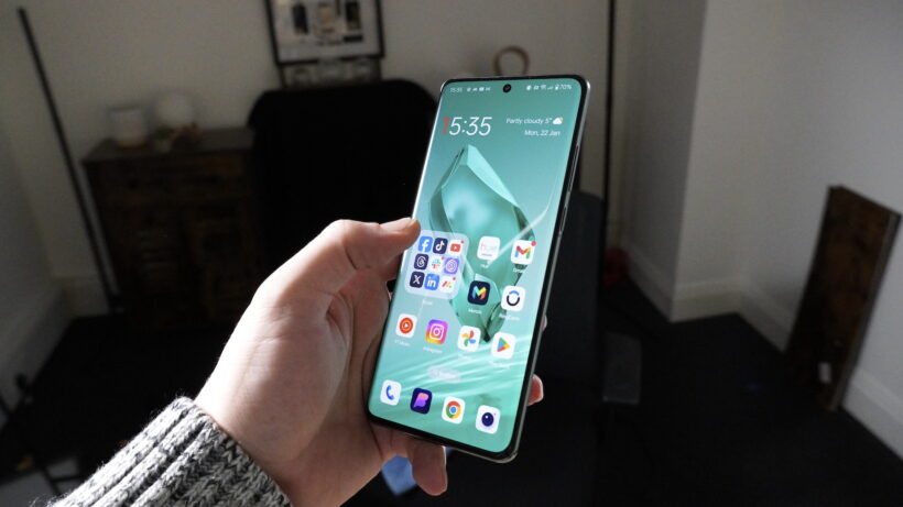 Использование OnePlus 12. Человек держит в руке смартфон OnePlus, на экране которого отображаются приложения.