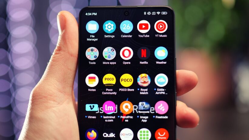 Приложения на Poco X6. Рука, в которой держится смартфон Poco X6 с яркими значками приложений.