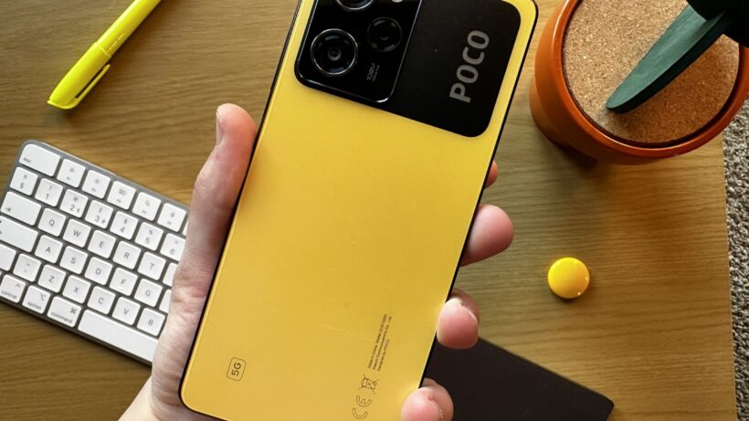 Poco X5 Pro. Рука, держащая смартфон Poco X5 Pro с желтой задней панелью.